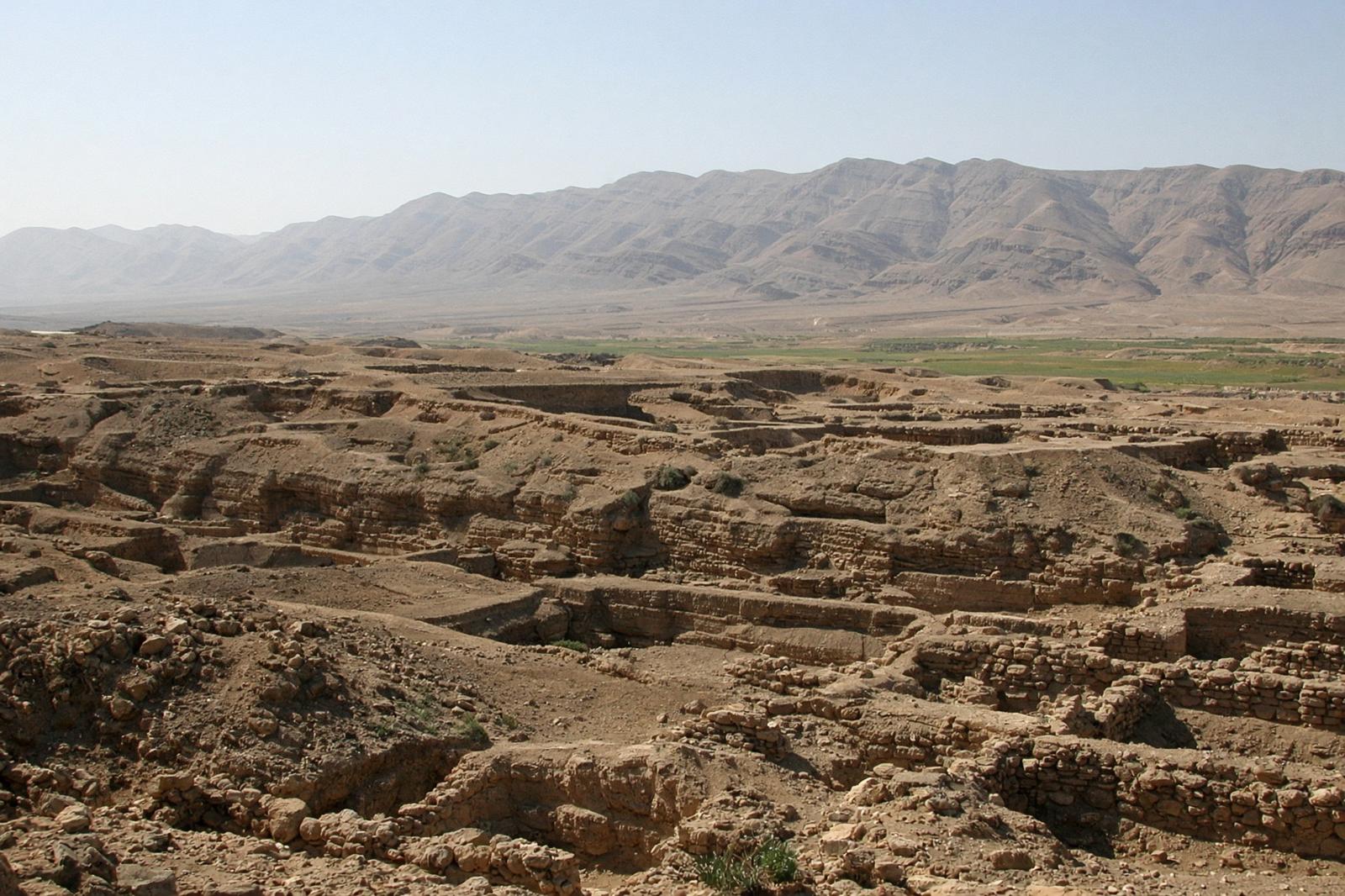 Excavated mudbrick and stone ruins of Jericho, with desert mountains beyond