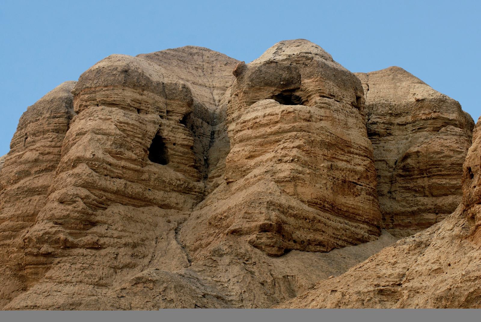 Layered desert cliffs at Qumran, with cave openings in the rock
